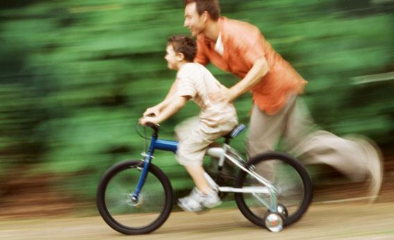 father teaching son how to ride a bicycle