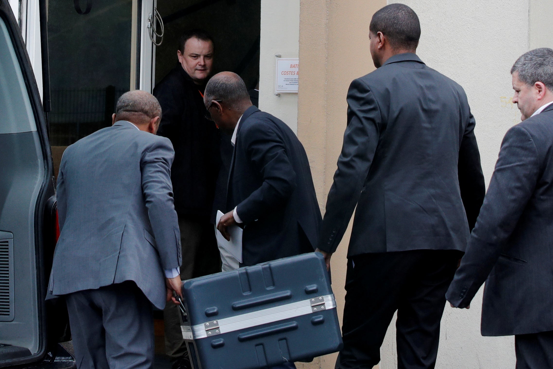 Men unload a case containing the black boxes from an SUV