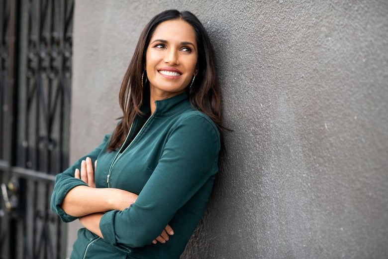 Padma Lakshmi leaning against the wall smiling