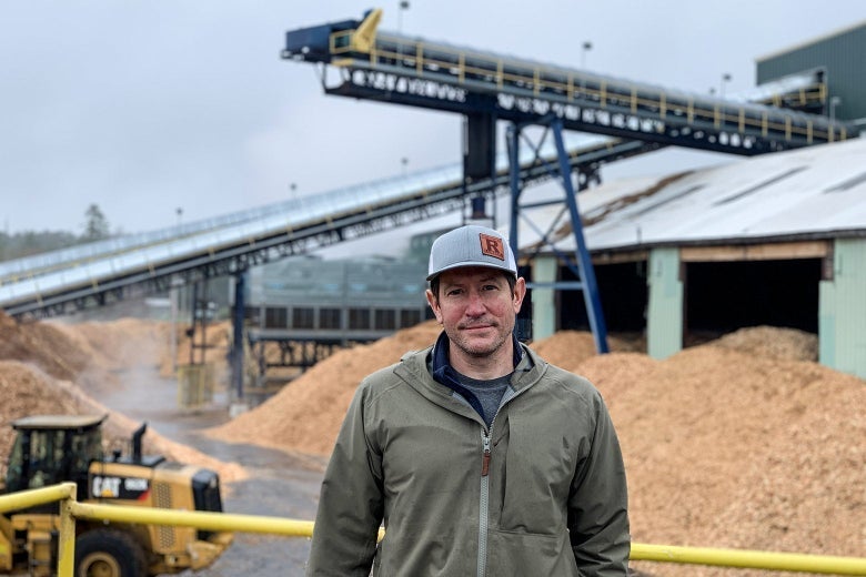 Alden Robbins stands in front of piles of chips outside on a cloudy day