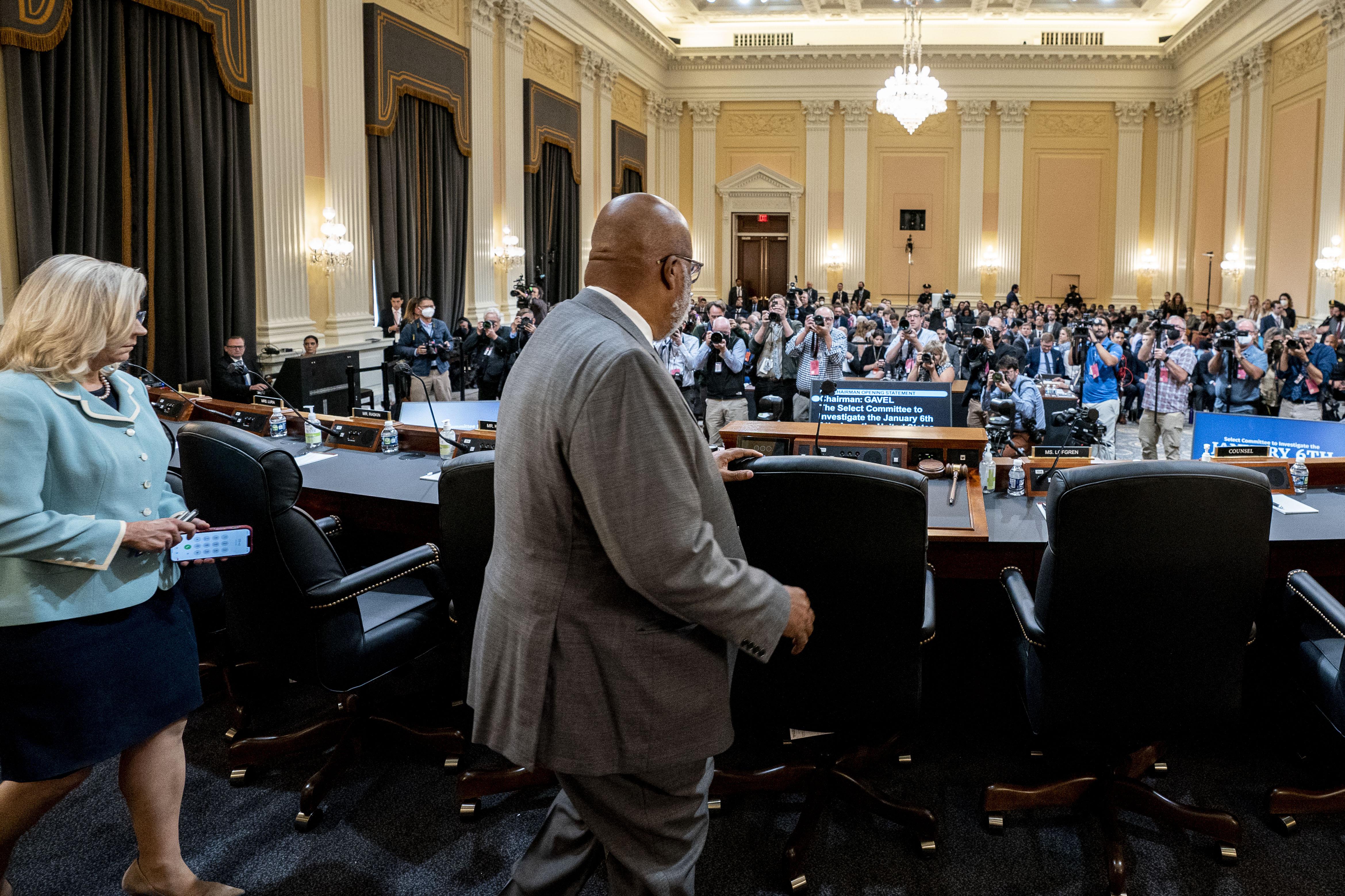 Thompson and Cheney seen from the side staring down from the podium at a packed committee room.