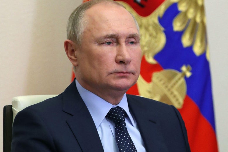 Putin grim-faced in front of the Russian flag.