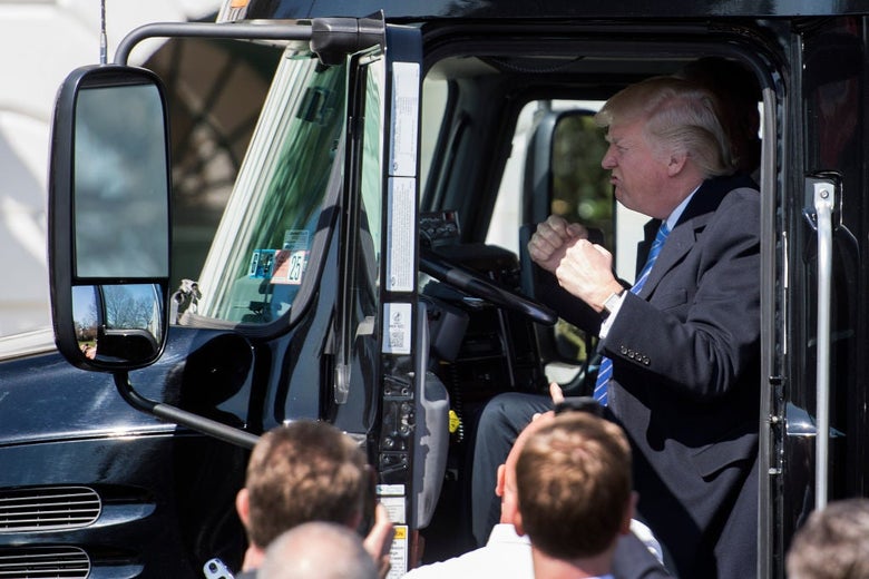 Trump clenches his fists and grunts while sitting in the cab of a semi truck parked in front of the White House.