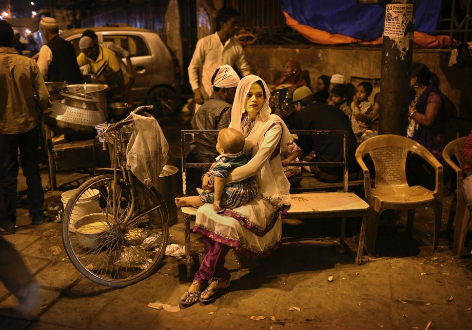 An Indian Muslim woman holds her child as she waits on a bench at a food stall in New Delhi, India, on March 14, 2013.