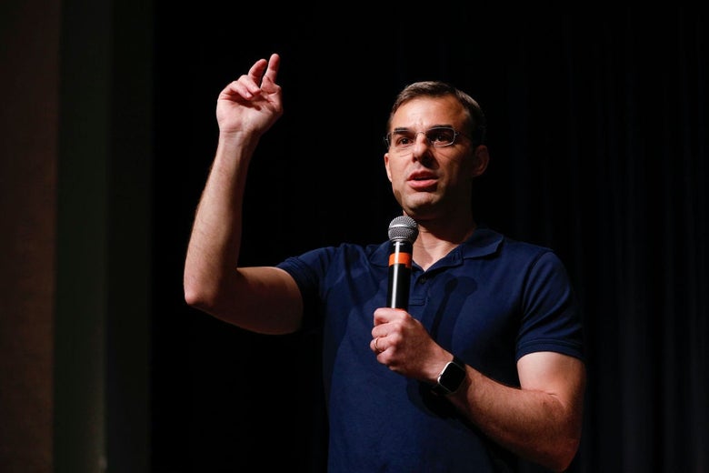 Amash, wearing a blue polo shirt and holding a microphone in one hand, gestures with the other while speaking.