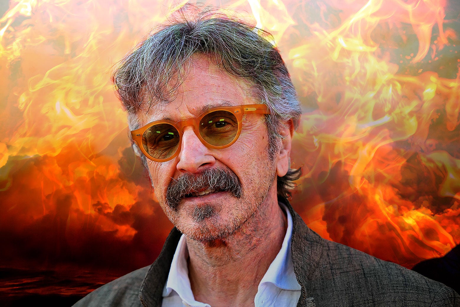 Marc Maron lacht met een zonnebril op en achter hem staat alles in brand.
