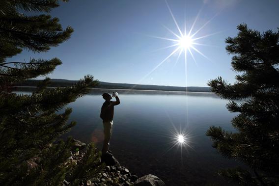 A hiker drinks from a water bottle in front of Heart Lake in the Red Mountains of Yellowstone National Park, Wyoming.