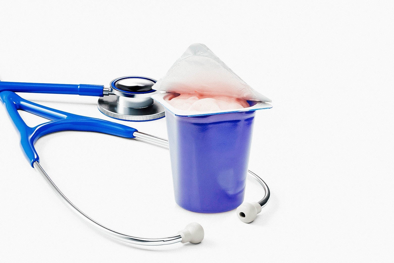 A stethoscope around an open single-serve container of yogurt.