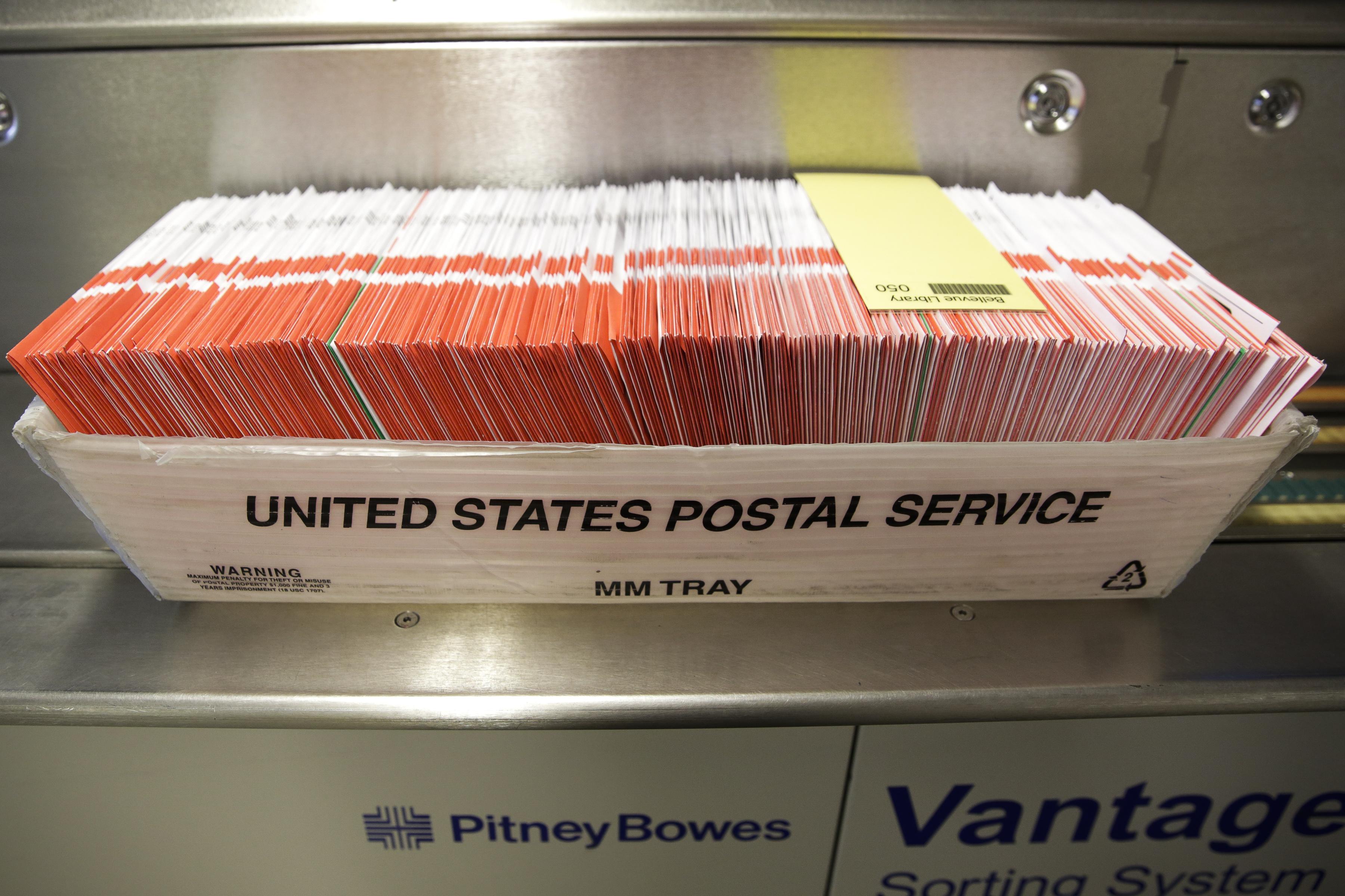 A box of ballots to be sorted are pictured in a U.S. Postal Service box.