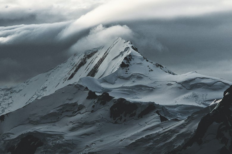 A snow-covered mountain under cloudy skies.