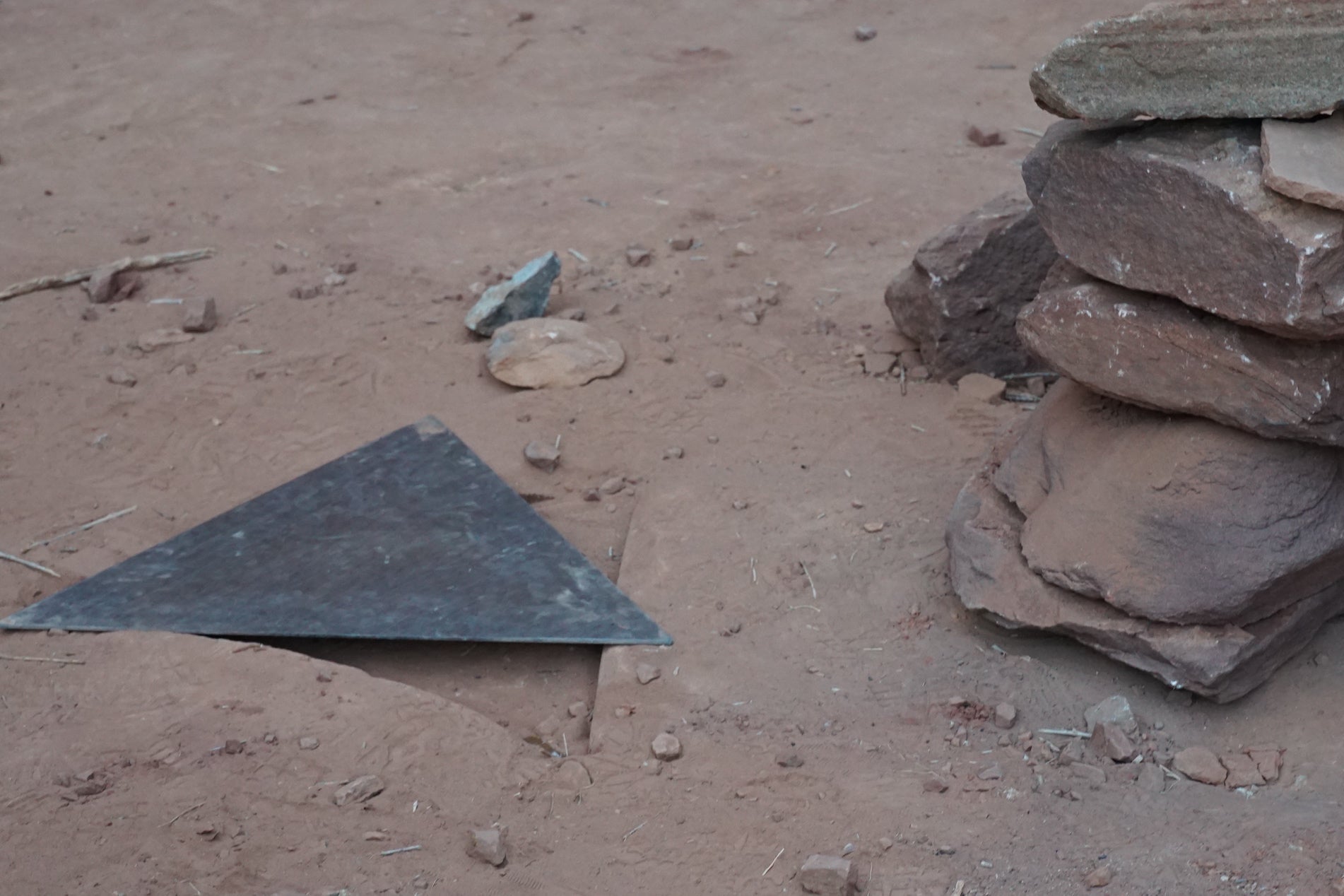 A triangular piece of metal next to a cairn
