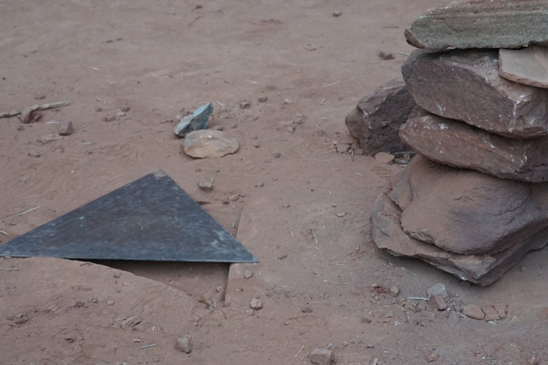 A triangular piece of metal next to a cairn