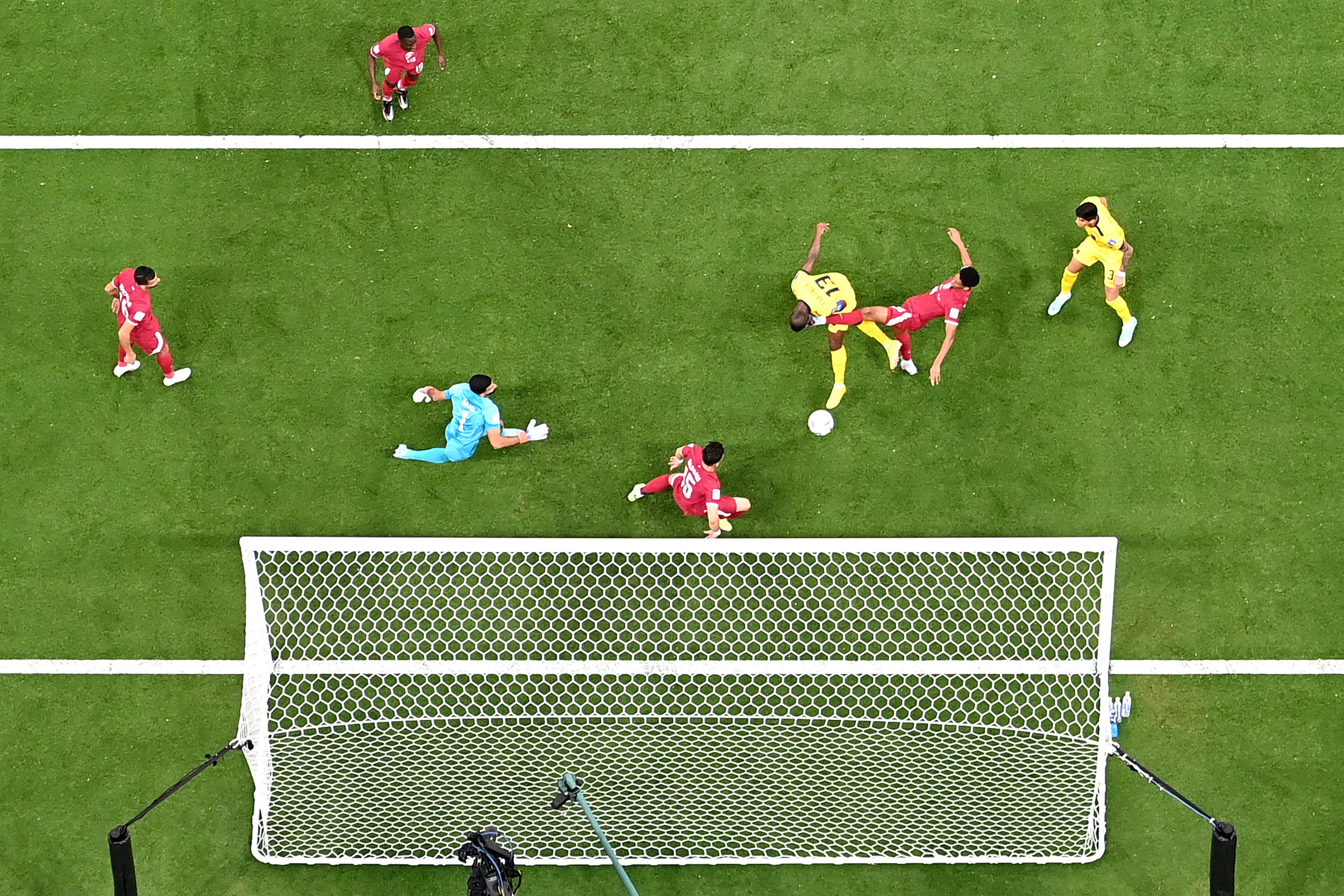 A bird's-eye view shot of a ball heading toward a soccer goal as several players are on the field.