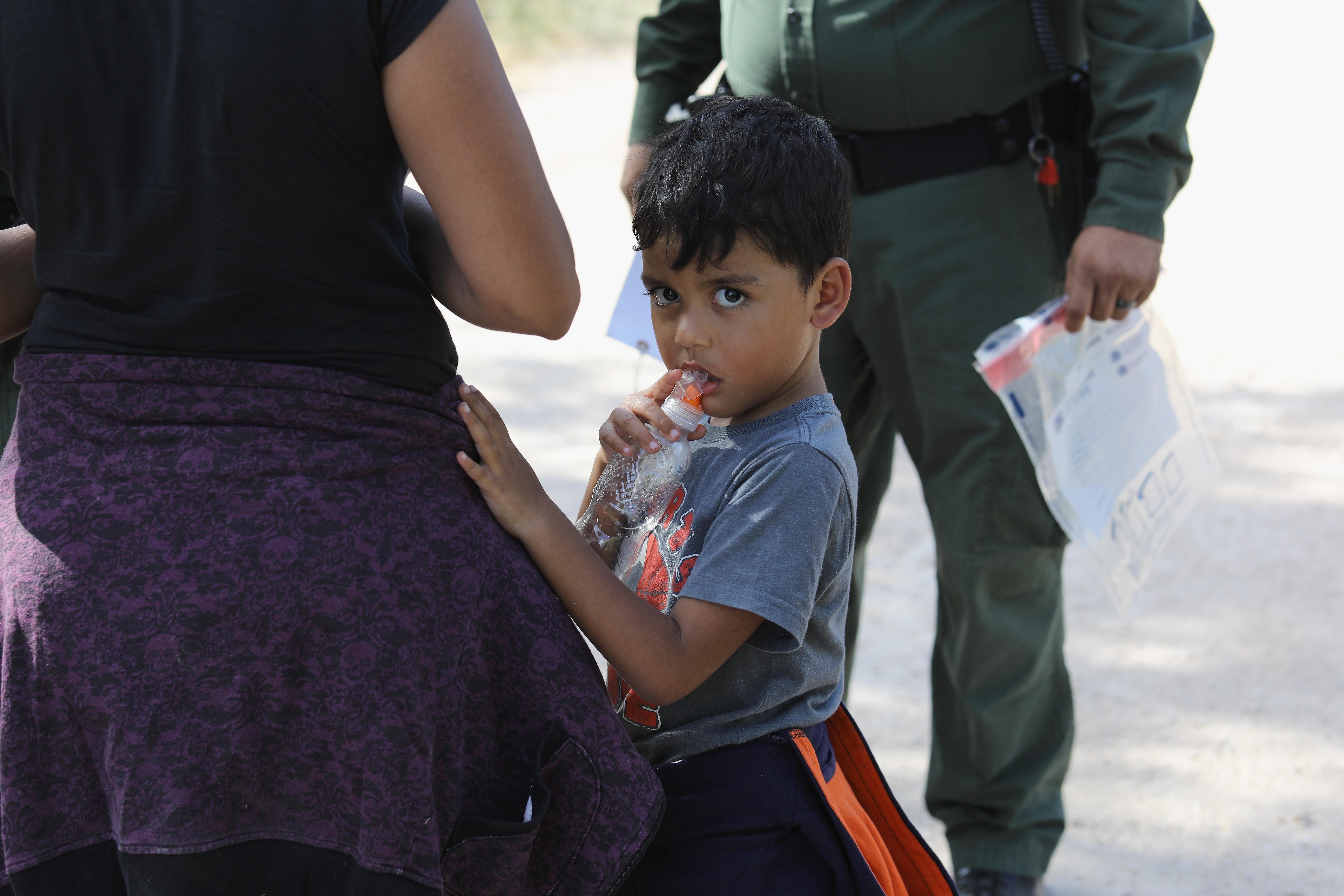 Central American asylum-seekers wait as U.S. Border Patrol agents take them into custody.