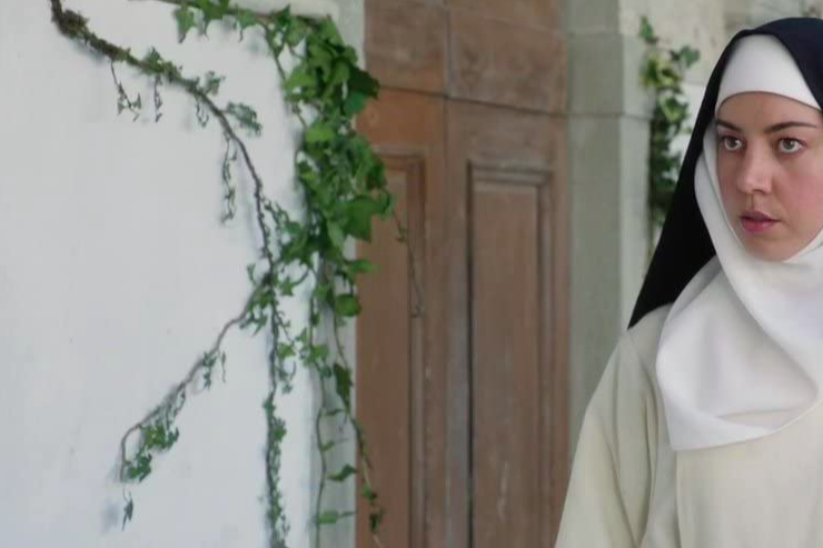 Aubrey Plaza wears a white nun's habit with a black hood.
