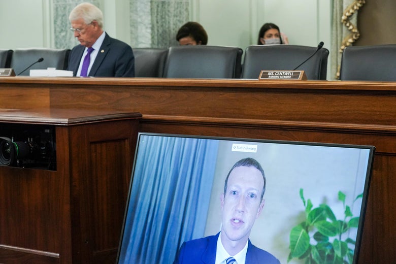 Mark Zuckerberg is on a large screen propped up against the desk where one senator sits.