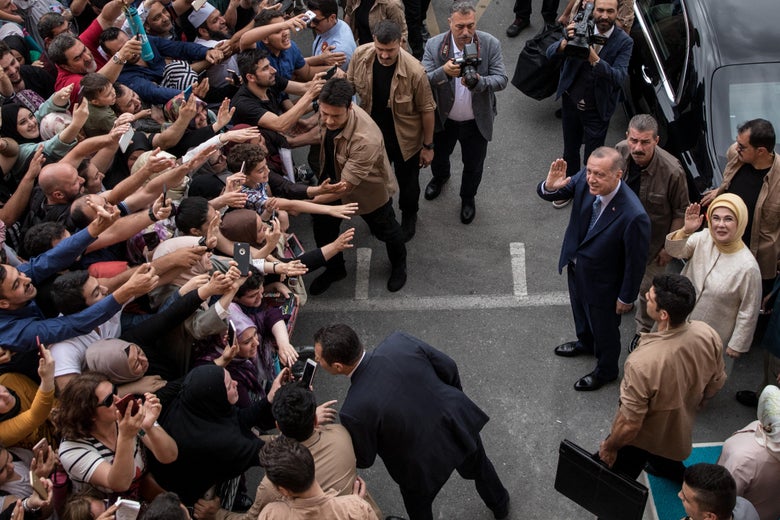 President Recep Tayyip Erdogan and wife, Emine Erdogan, wave to supporters besides a black car. 