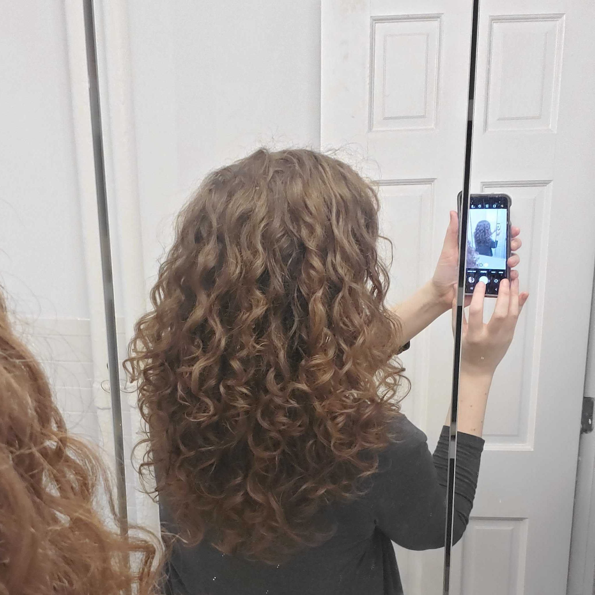 Reflection of wavy hair softened with a pasta strainer from behind.