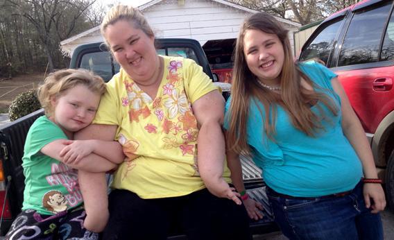 Honey Boo Boo (Alana Thompson), Mama (June Shannon), and Chubbs (Jessica Shannon) sitting on a pickup truck bed in the Season 2 Premiere of Here Comes Honey Boo Boo.