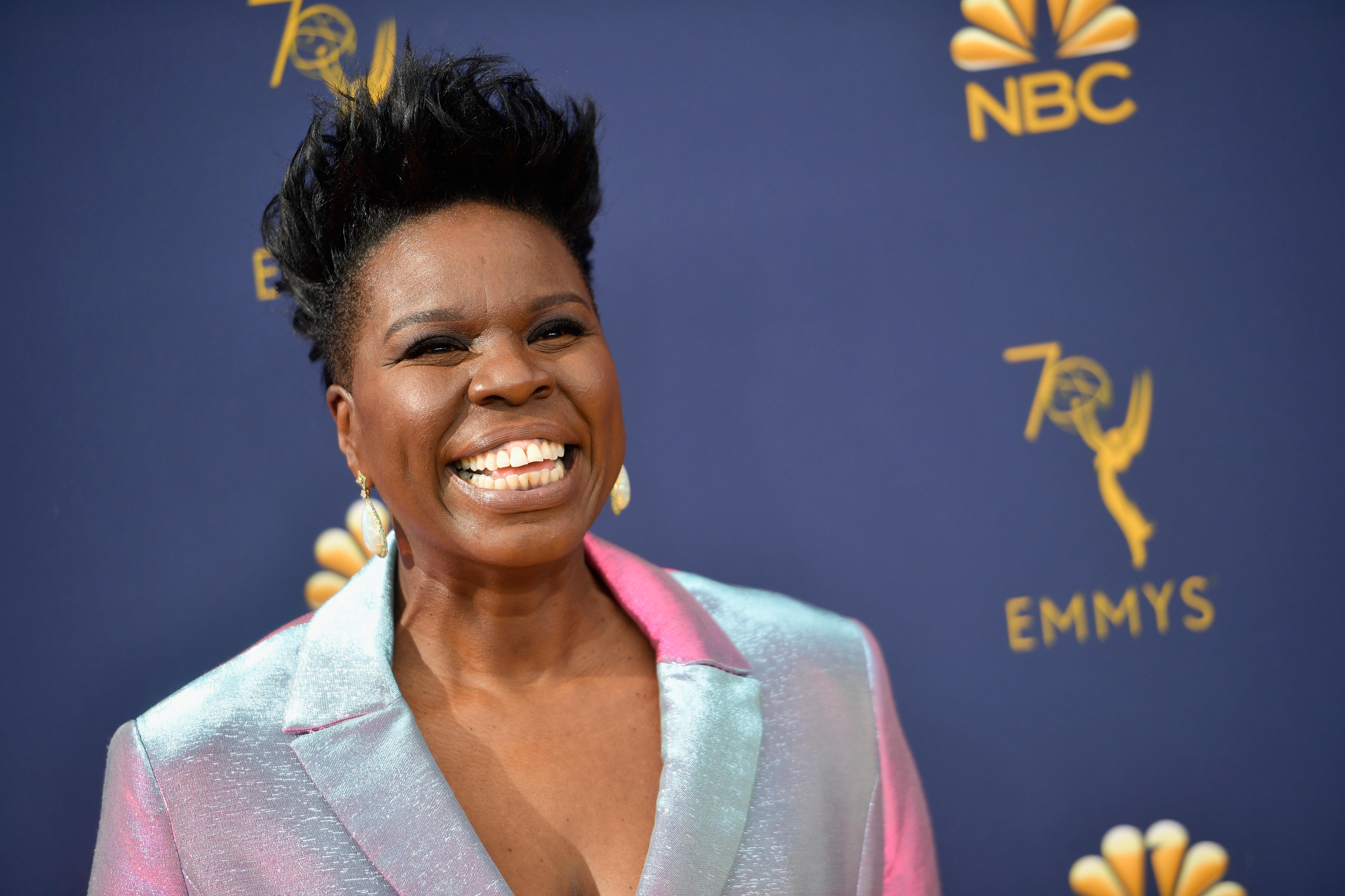 Leslie Jones smiles on the Emmy's red carpet, wearing an iridescent silver suit.