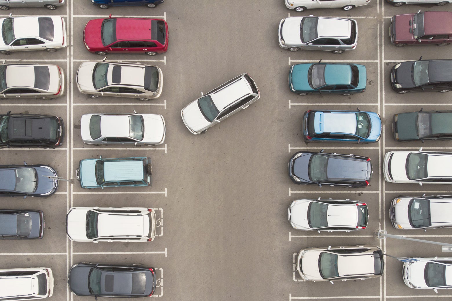A bird's-eye view of a full parking lot, with one car searching for a spot.