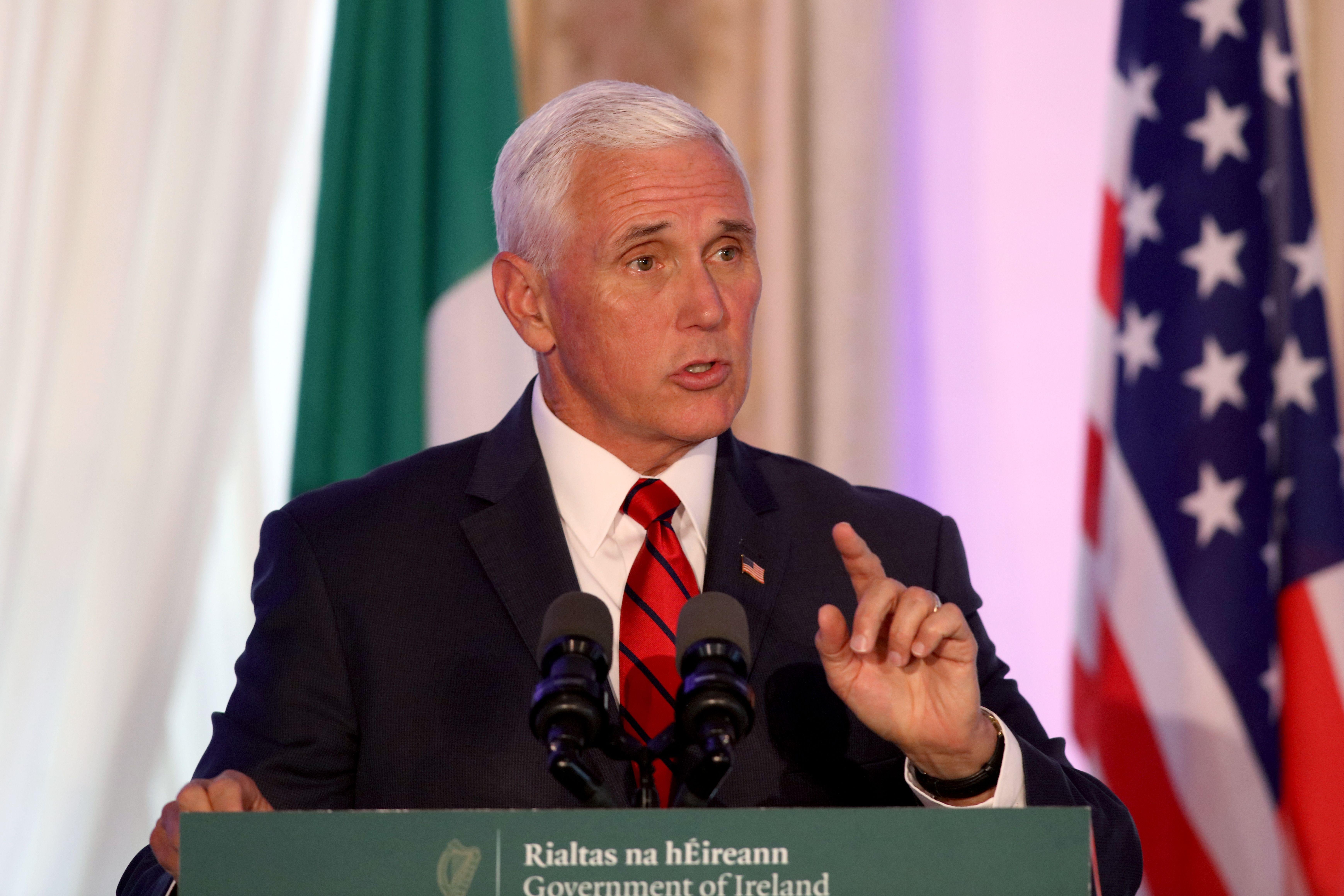 Vice President Mike Pence speaks while standing in front of Irish and American flags.