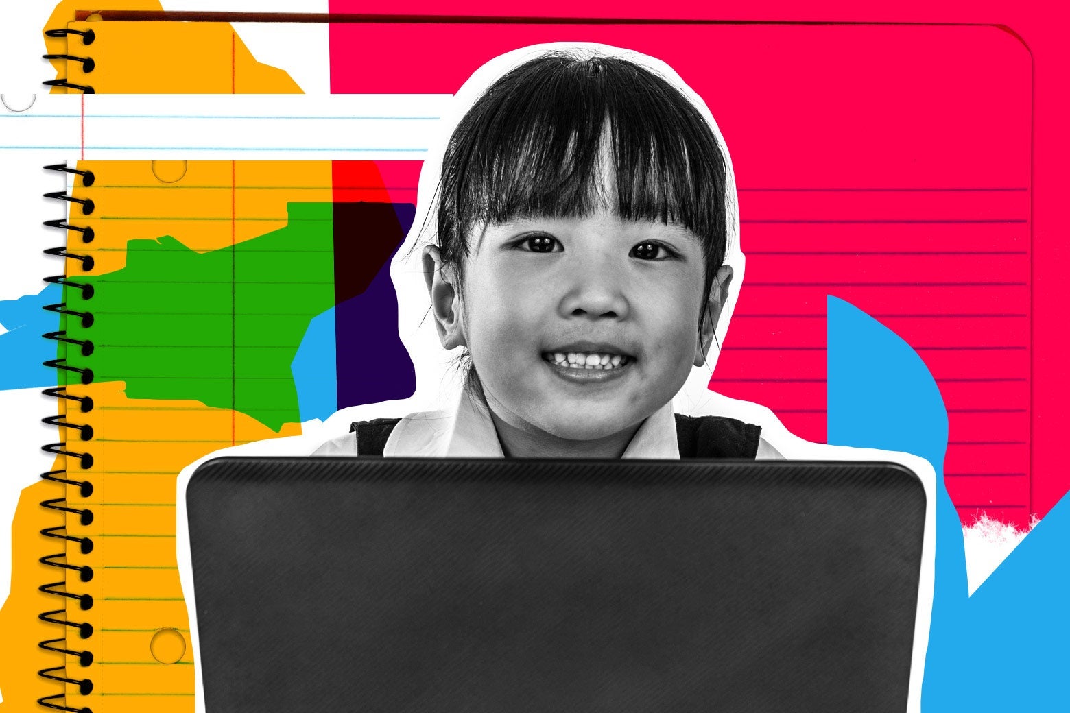 A girl smiles from behind a laptop.