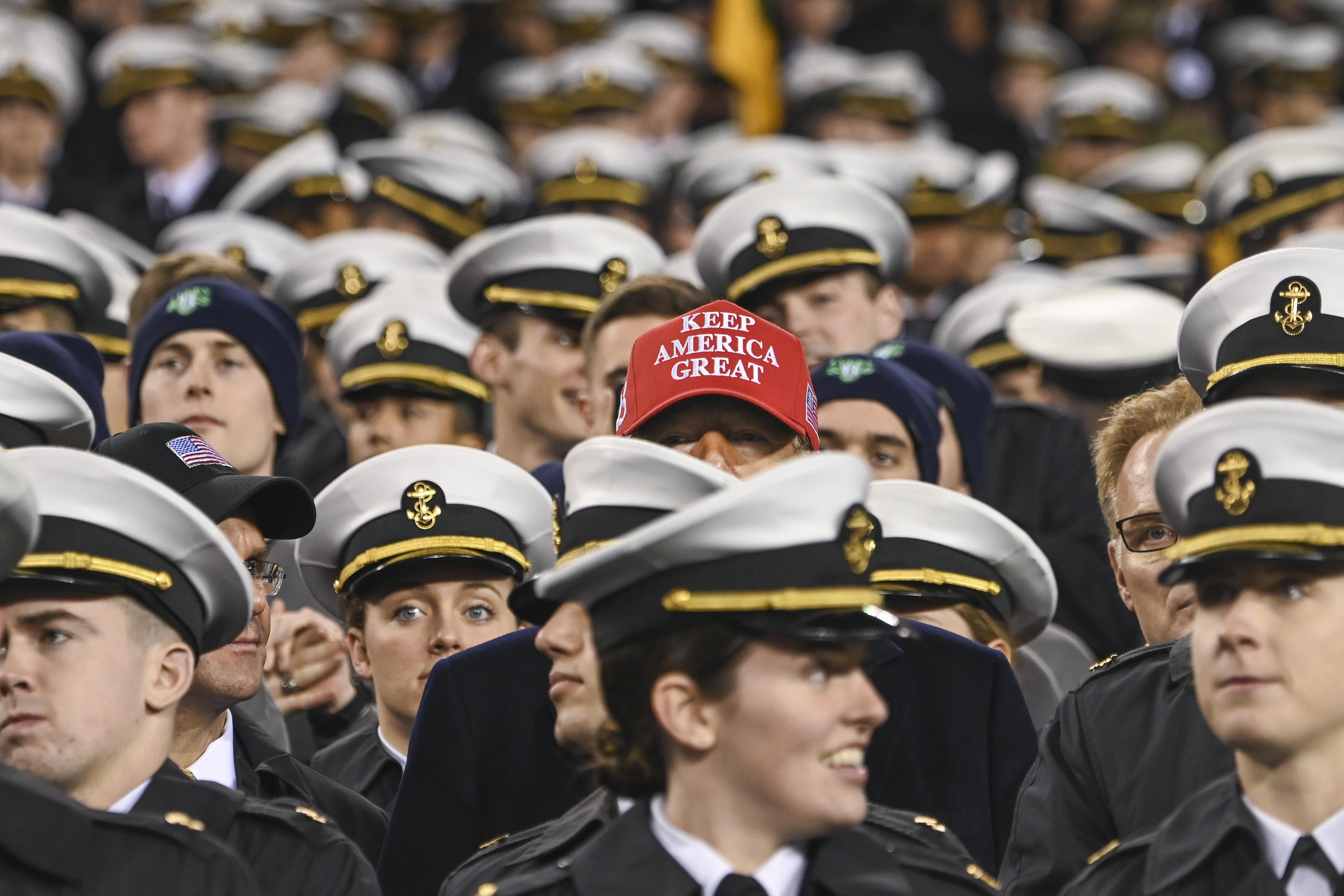 A "Keep America Great" hat appears among a sea of military caps.