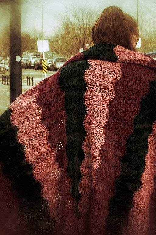 A woman wears a light blanket outside on a street. This image appears in the book EXPOSURE: Homelessness through the lens of art & poetry.