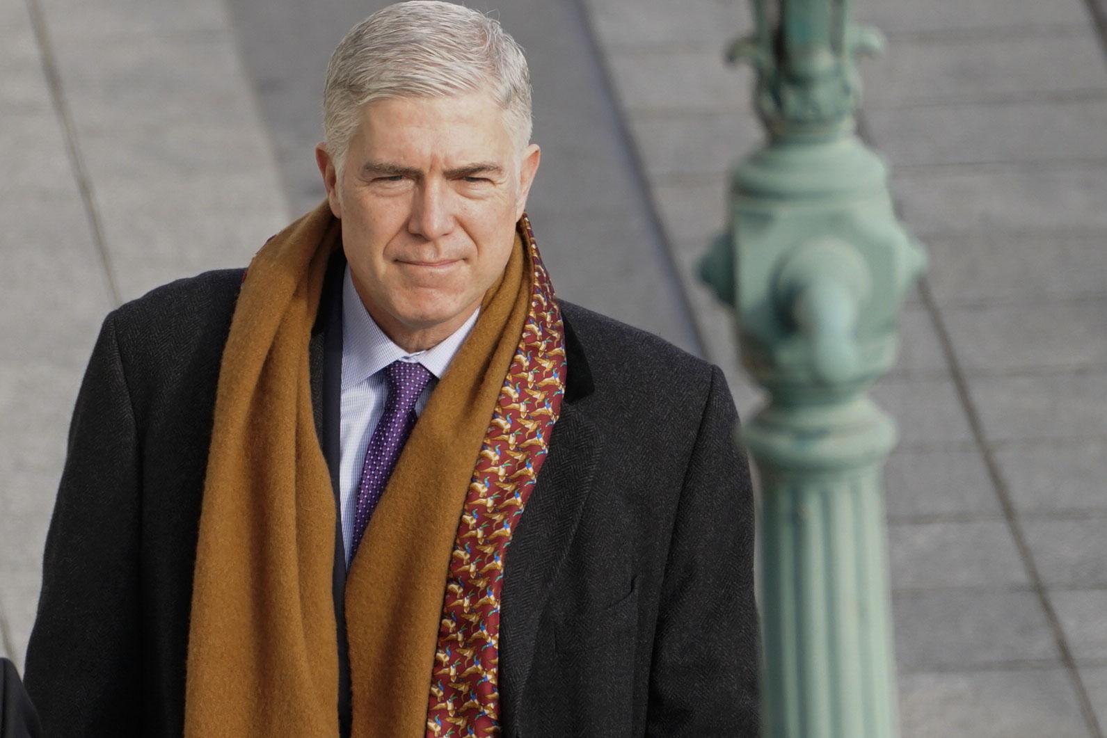 Gorsuch wearing a scarf and a suit and a soot-eating grin.