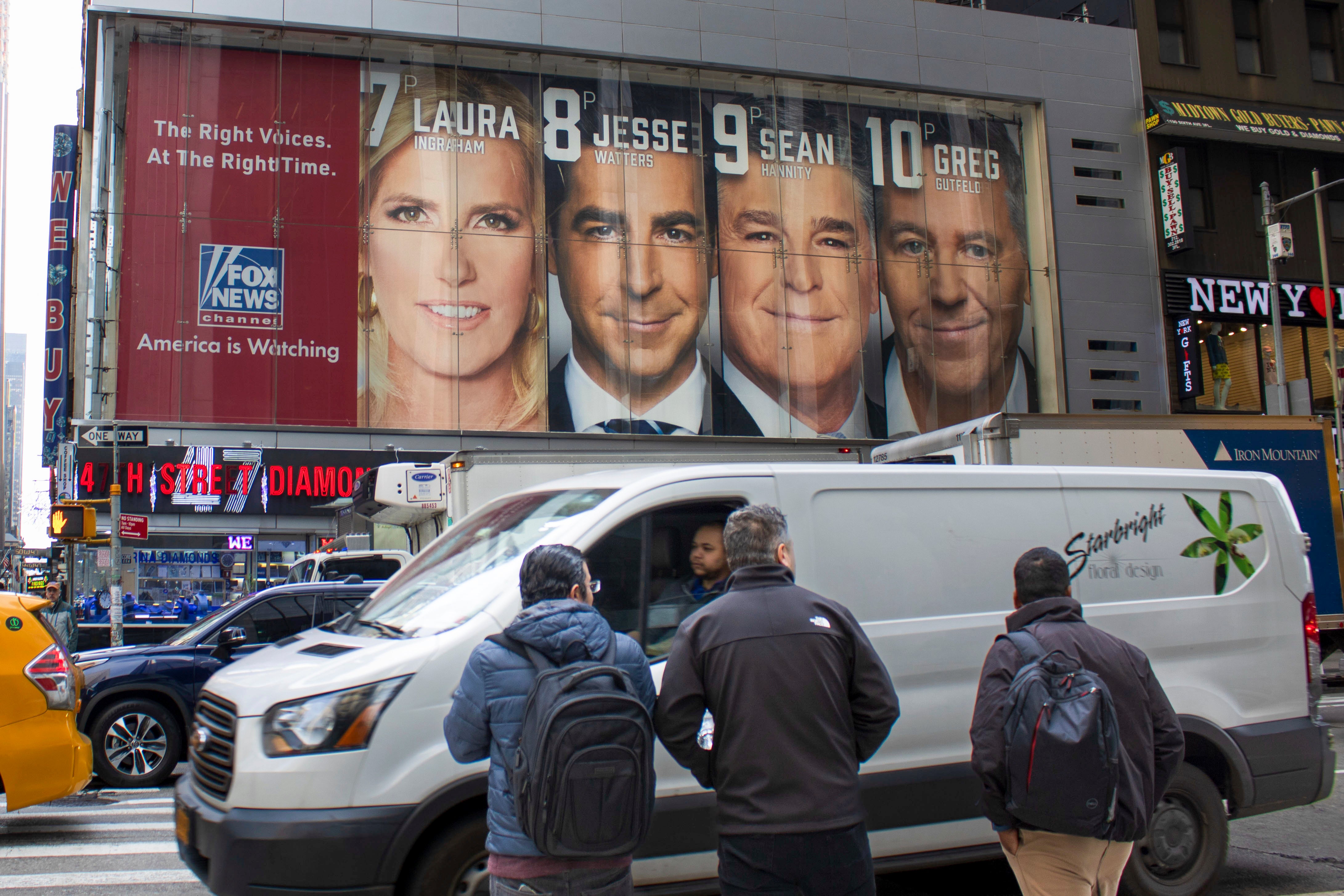 Fox News billboard in a city that displays the network's heavy hitters: Laura Ingraham, Jesse Watters, Sean Hannity, and Greg Gutfeld.