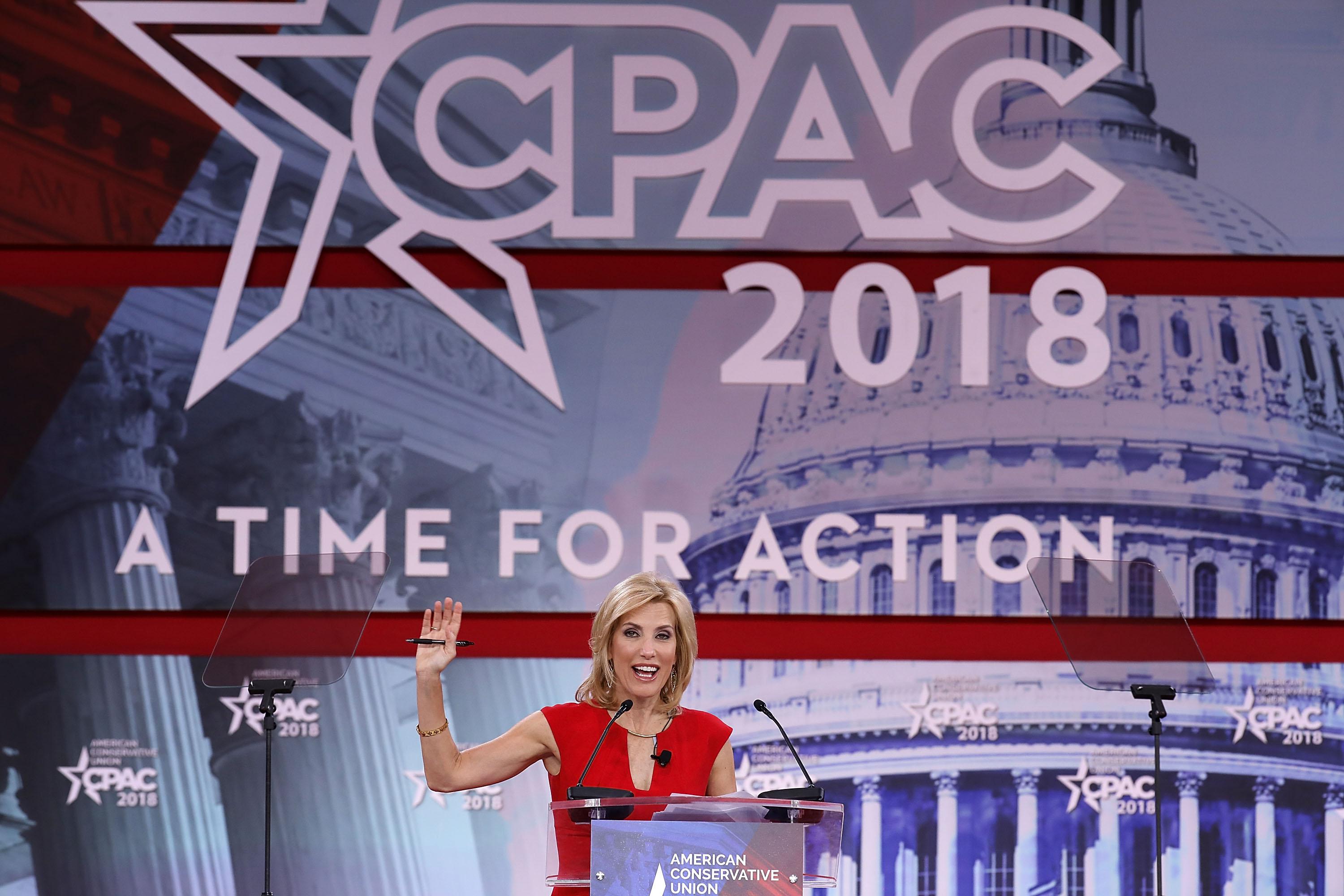 Laura Ingraham raises her right hand while addressing the crowd at CPAC 2018.