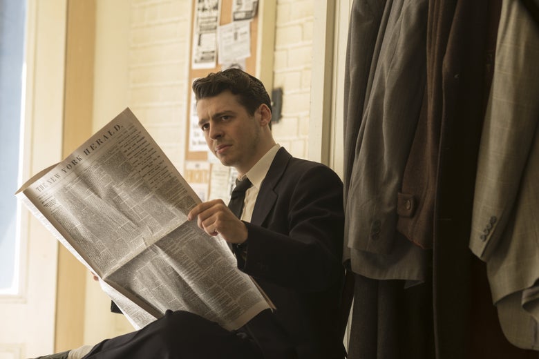 A man in a suit reads a newspaper.