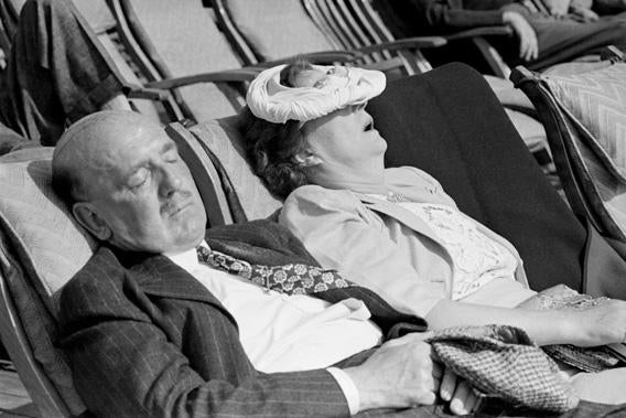 An American couple sleeping in the Atlantic sunlight on board the Cunard liner Queen Elizabeth as she makes her way to Britain. 