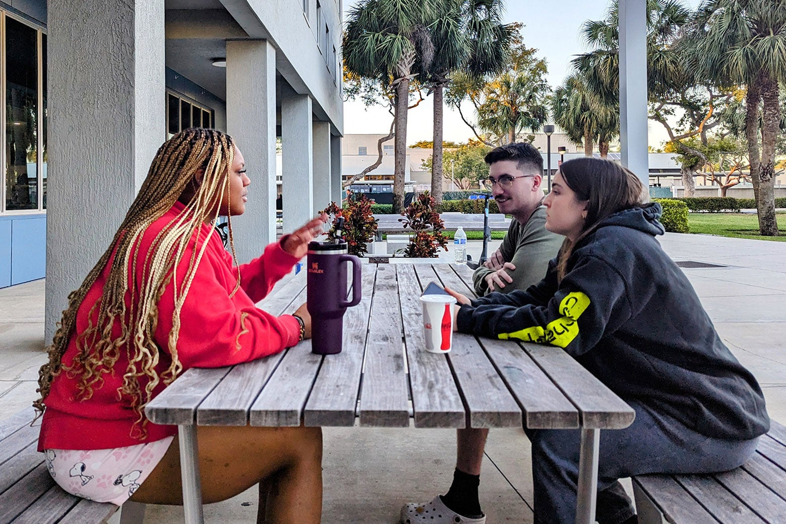 A group of three college students sitting at a picnic table.