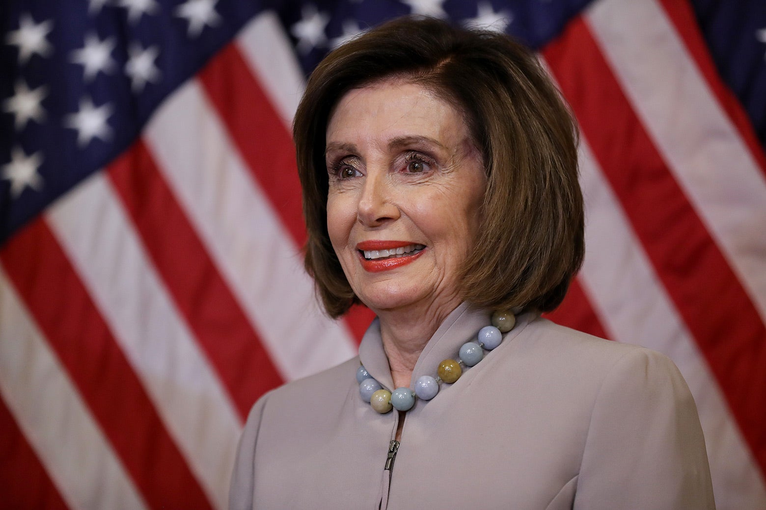 Nancy Pelosi stands in front of an American flag.