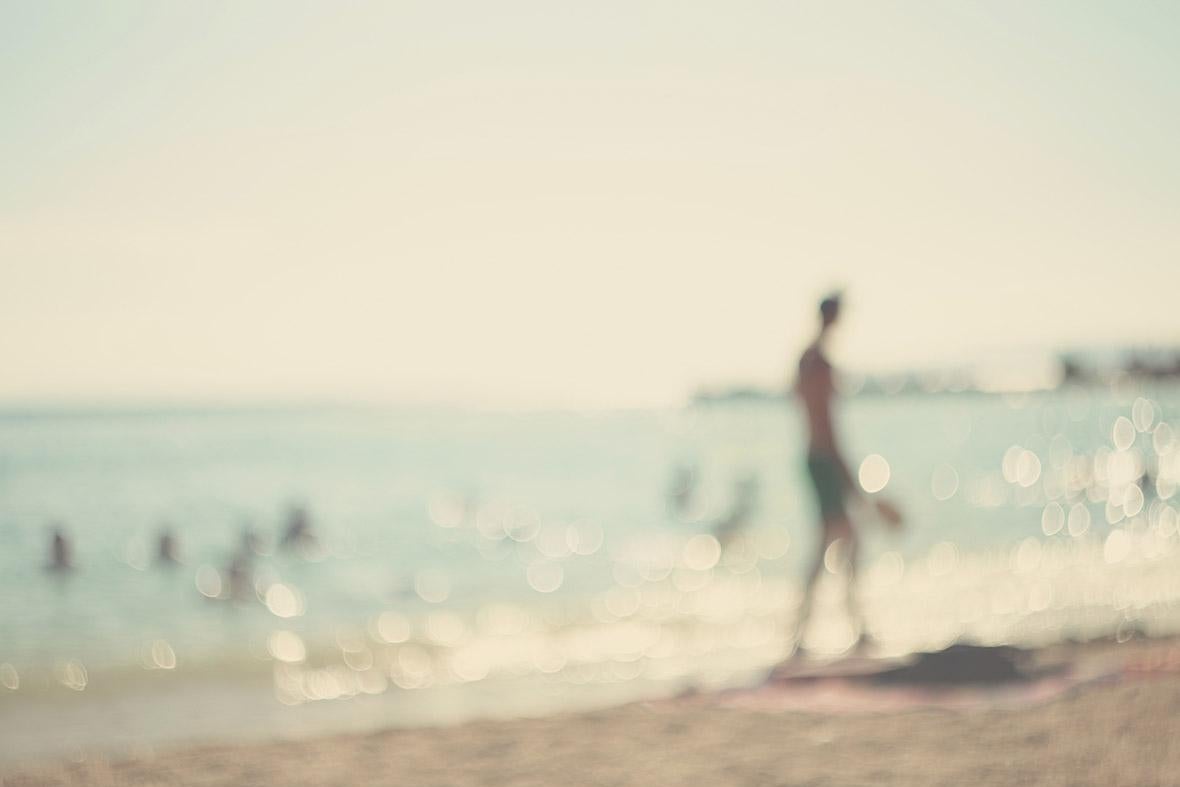 A person walks along the beach in a blurry photograph.