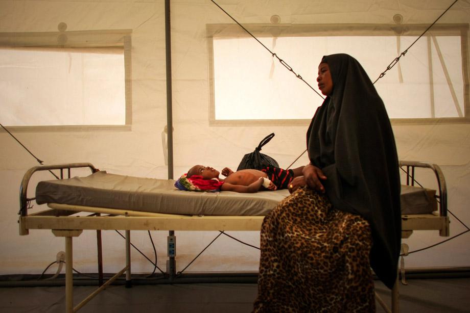 A Somali woman sits on a bed where her son has been admitted to a tented-hospital ward at a free Outpatient's Department (OPD) medical clinic at the headquarters of the Burundi Contingent serving with the African Union Mission in Somalia (AMISOM) at the former National University in the Somali capital Mogadishu, March 4, 2013.