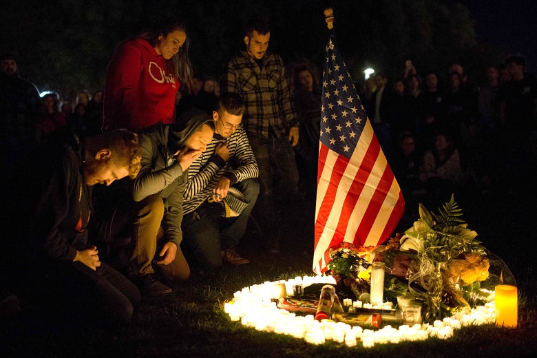 People kneel around an American flag and candles.