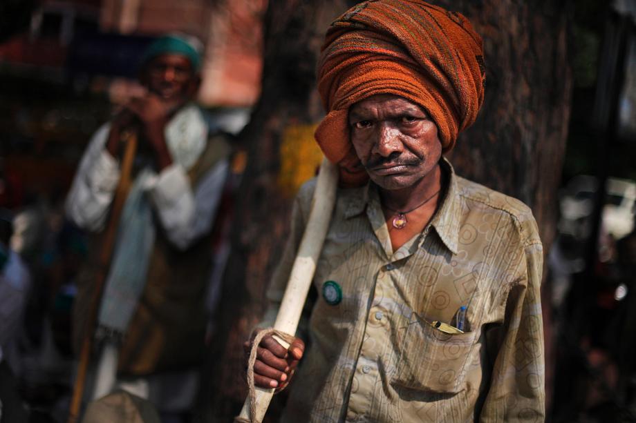 An Indian farmer, armed with a stick, reacts to the camera as he listens to a speaker, unseen, during a protest near the Indian Parliament in New Delhi, India on March 20, 2013. 
