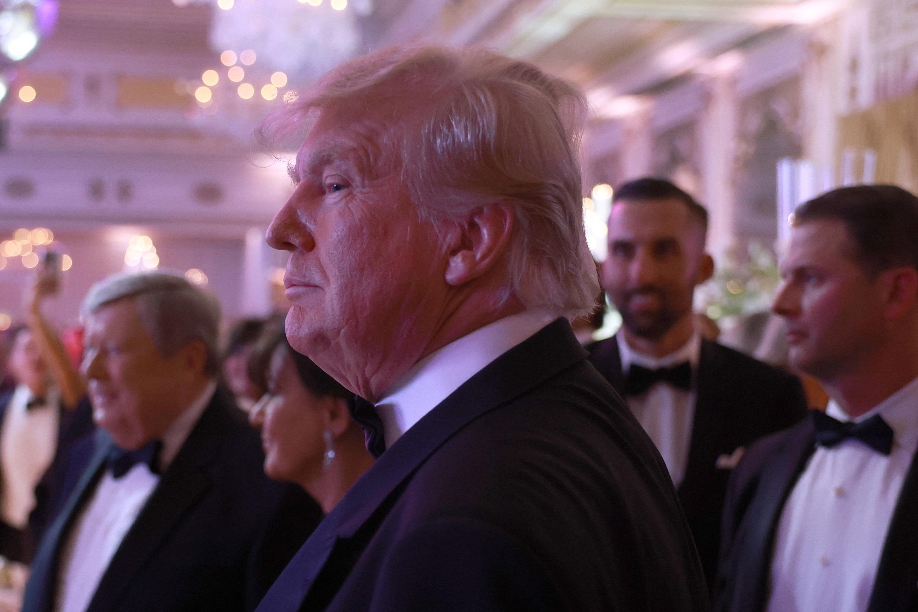 Donald Trump surrounded by people wearing formalwear.