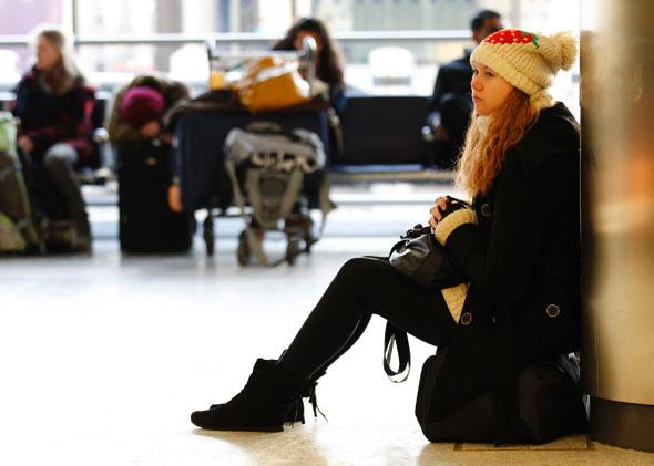 A girl sits on her bag as she waits for her flight at Edinburgh Airport, Scotland, Dec. 20, 2010.