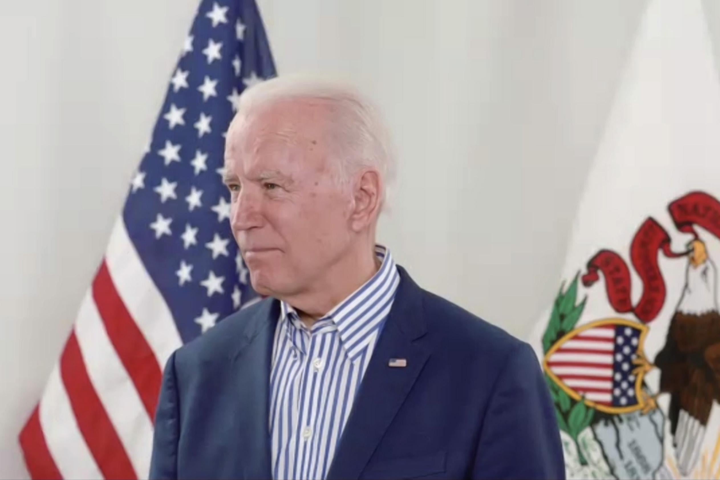 Biden stands with the American flag and Illinois flag behind him