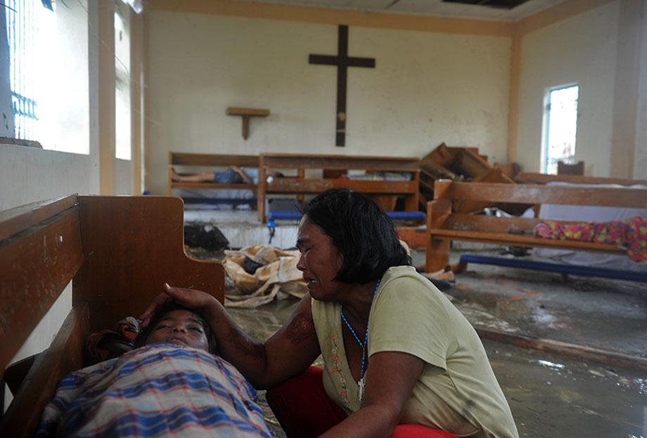 A mother weeps beside the dead body of her son at a chapel in the aftermath of Super Typhoon Haiyan in Tacloban, eastern island of Leyte on November 9, 2013. 
