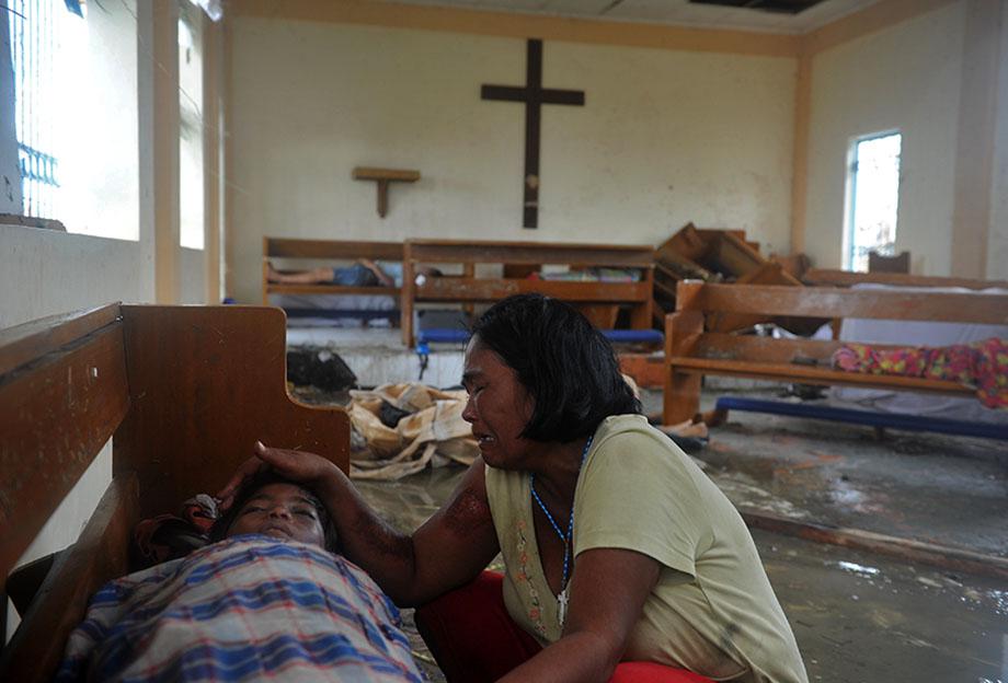 A mother weeps beside the dead body of her son at a chapel in the aftermath of Super Typhoon Haiyan in Tacloban, eastern island of Leyte on November 9, 2013.