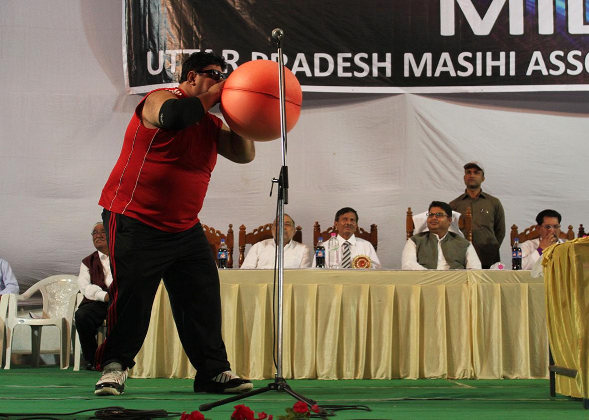 Manoj blowing up a rubber hot water bottle bag like a balloon.