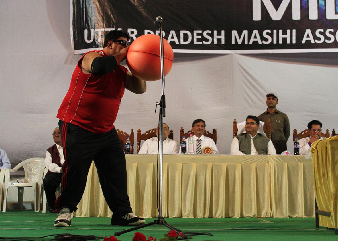 Manoj blowing up a rubber hot water bottle bag like a balloon.