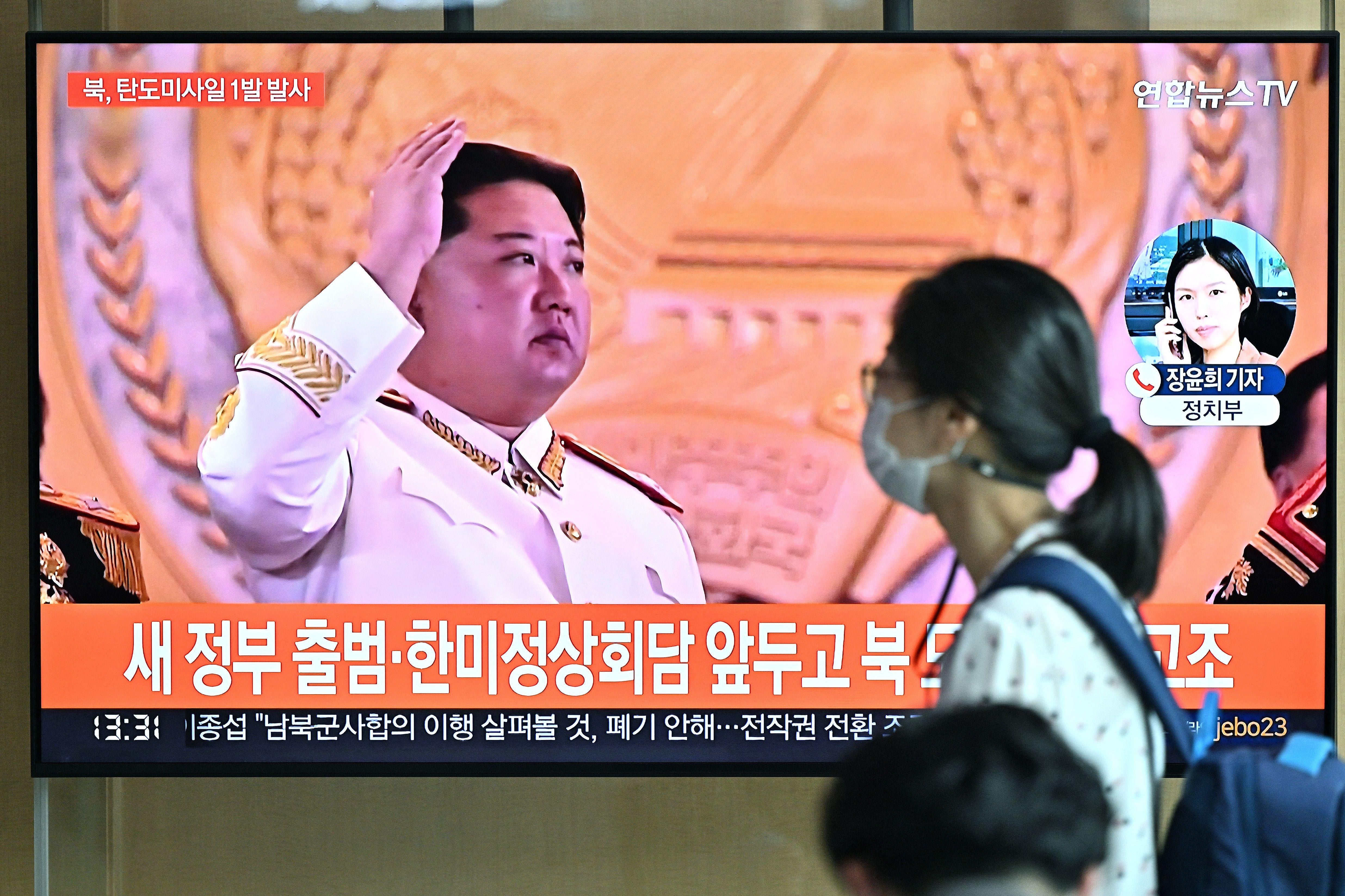 TOPSHOT - A woman walks past a television screen showing a news broadcast with file footage of North Korean leader Kim Jong Un, at a railway station in Seoul on May 4, 2022. - North Korea fired a ballistic missile on May 4, South Korea's military said, just a week after leader Kim Jong Un vowed to boost Pyongyang's nuclear arsenal at the "fastest possible speed". (Photo by Jung Yeon-je / AFP) (Photo by JUNG YEON-JE/AFP via Getty Images)