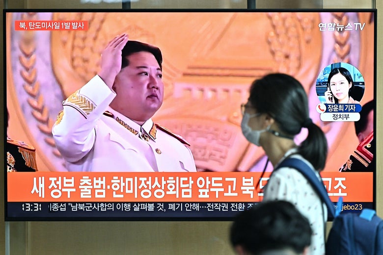 TOPSHOT - A woman walks past a television screen showing a news broadcast with file footage of North Korean leader Kim Jong Un, at a railway station in Seoul on May 4, 2022. - North Korea fired a ballistic missile on May 4, South Korea's military said, just a week after leader Kim Jong Un vowed to boost Pyongyang's nuclear arsenal at the "fastest possible speed". (Photo by Jung Yeon-je / AFP) (Photo by JUNG YEON-JE/AFP via Getty Images)