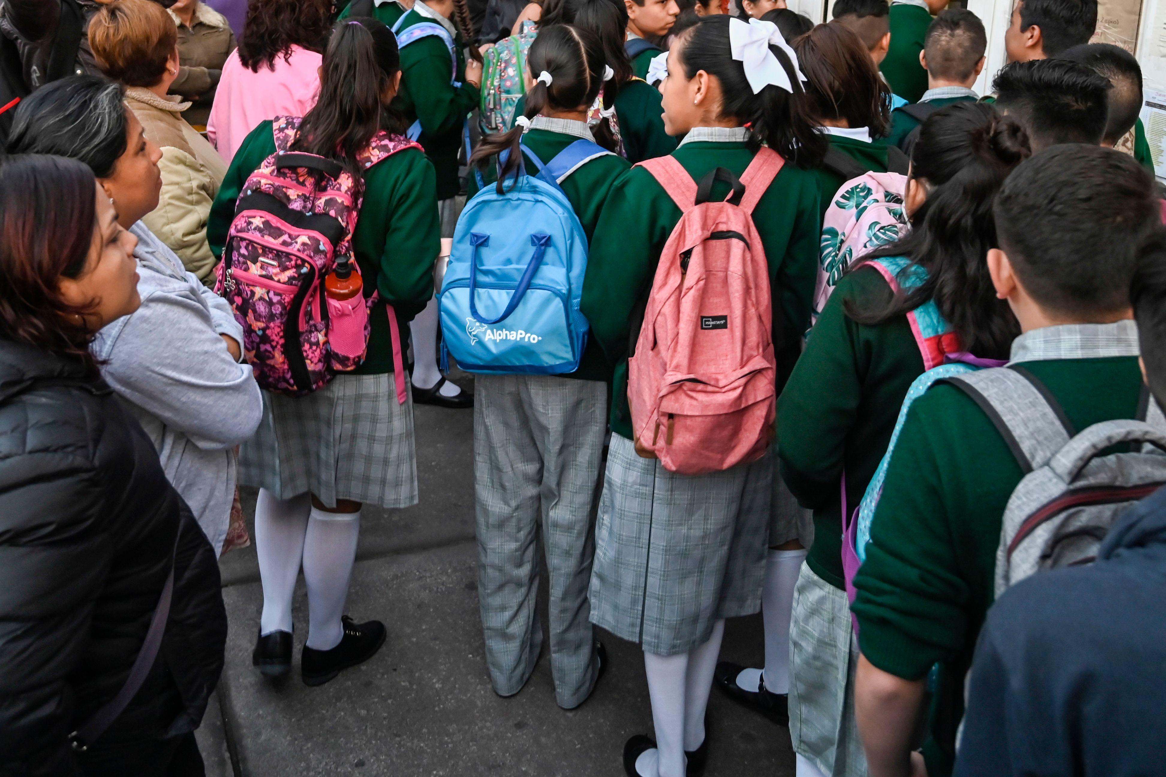 A crowd of uniformed schoolchildren including girls wearing skirts
